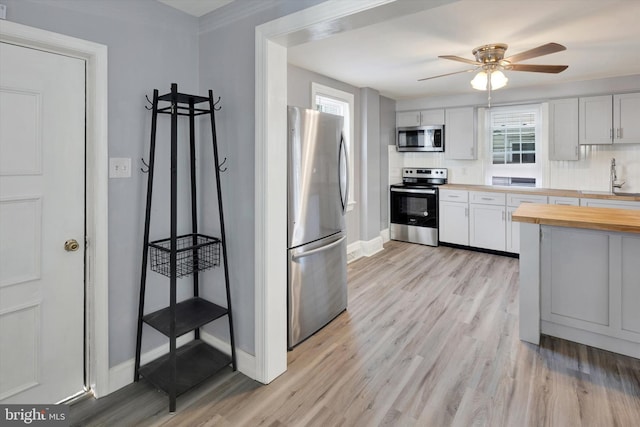 kitchen with butcher block countertops, stainless steel appliances, light hardwood / wood-style floors, and white cabinets