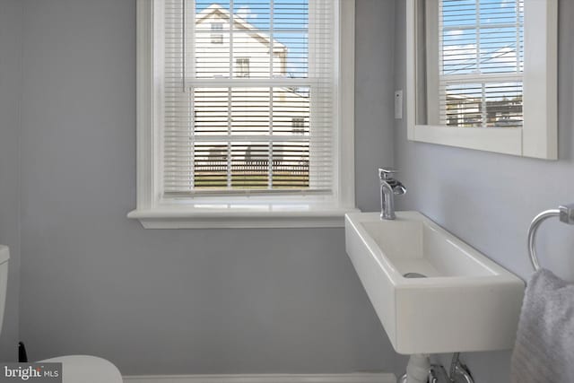 bathroom featuring a healthy amount of sunlight, sink, and toilet