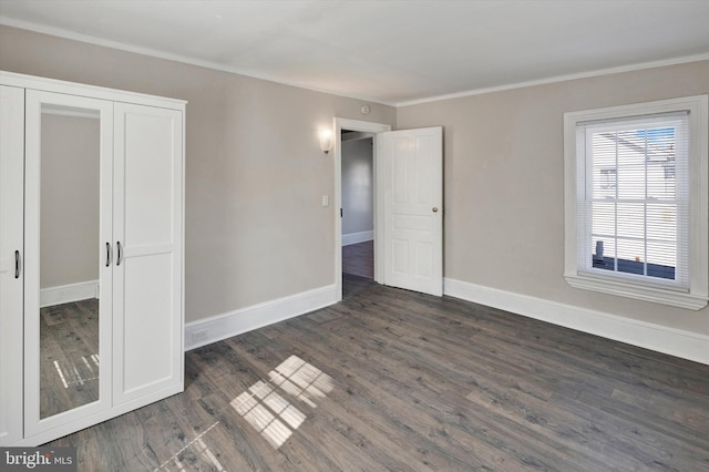 unfurnished bedroom with a closet, ornamental molding, and dark wood-type flooring