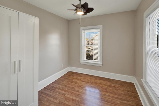 unfurnished bedroom with multiple windows, hardwood / wood-style flooring, and ceiling fan