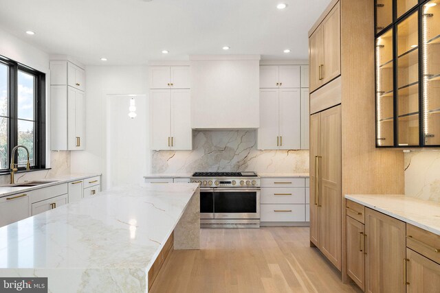 kitchen featuring stainless steel range, white cabinetry, and sink