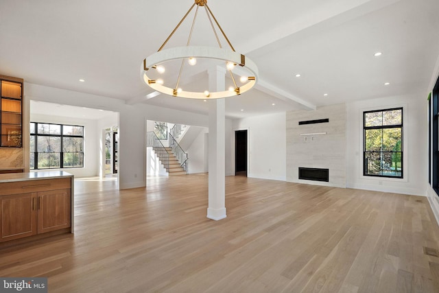 unfurnished living room featuring light hardwood / wood-style flooring, a tile fireplace, and a wealth of natural light