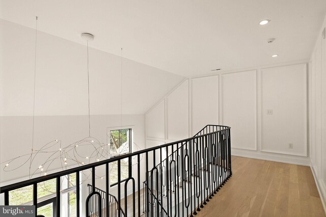 hallway featuring lofted ceiling and light hardwood / wood-style flooring