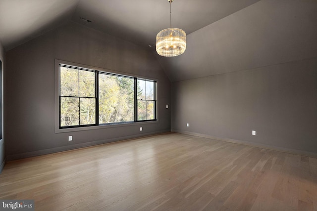 additional living space featuring a chandelier, vaulted ceiling, and light hardwood / wood-style floors