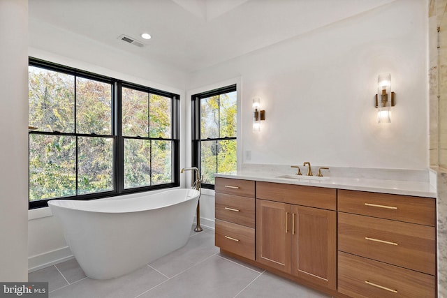 bathroom with a wealth of natural light, vanity, a tub, and tile patterned floors