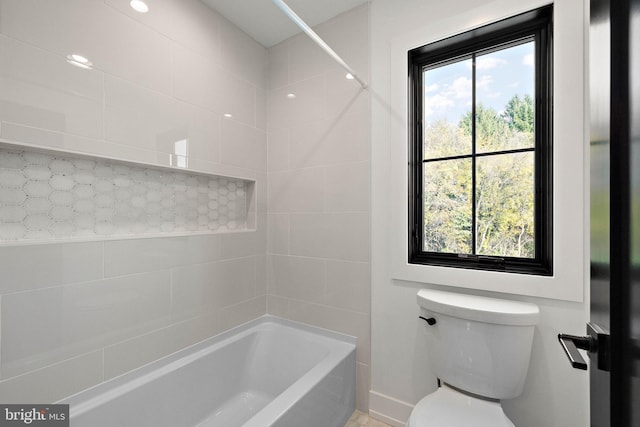 bathroom featuring a healthy amount of sunlight, tiled shower / bath, and toilet