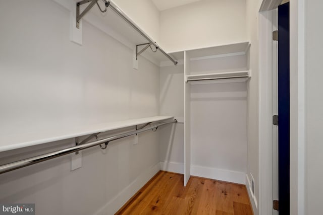 walk in closet with light hardwood / wood-style floors