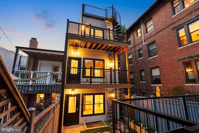 back house at dusk with a balcony