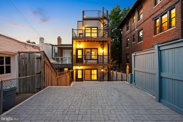 back house at dusk with a balcony