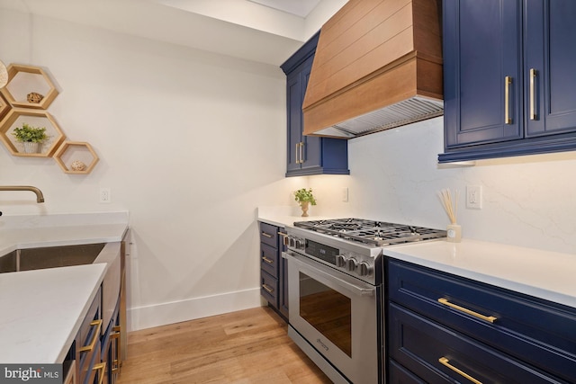 kitchen featuring blue cabinetry, custom range hood, light wood-type flooring, and high end stainless steel range