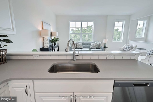 kitchen with kitchen peninsula, white cabinets, stainless steel dishwasher, and sink