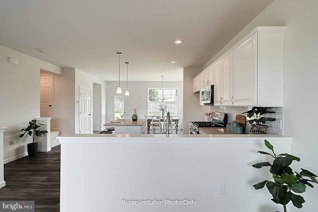 kitchen with stainless steel appliances, dark hardwood / wood-style flooring, kitchen peninsula, and white cabinets