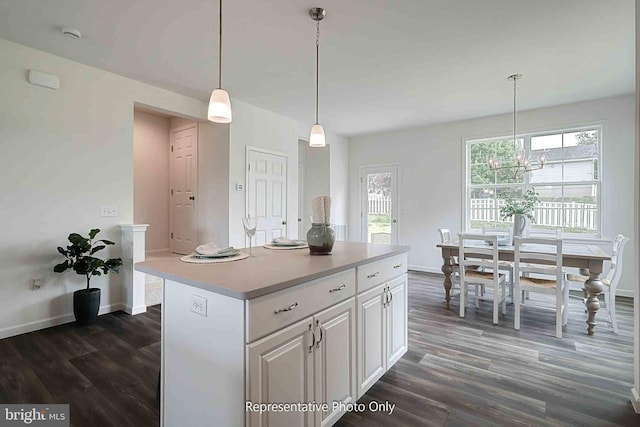 kitchen with a center island, white cabinets, pendant lighting, and dark hardwood / wood-style flooring