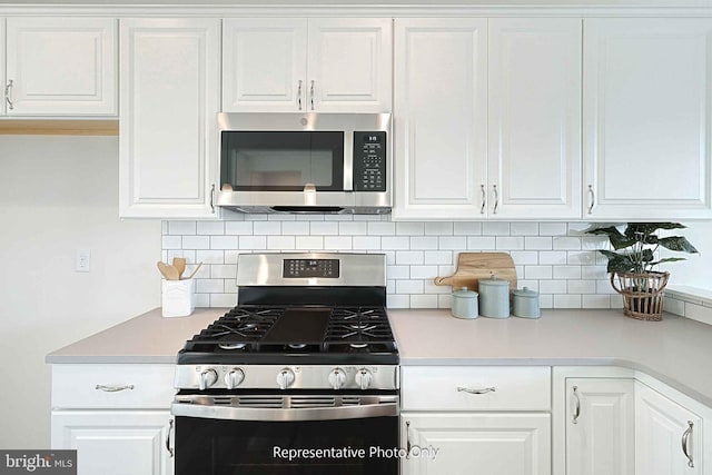 kitchen with white cabinetry, stainless steel appliances, and backsplash