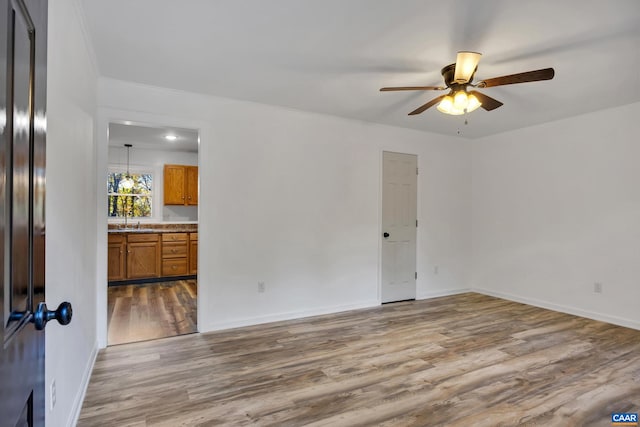 unfurnished room featuring ceiling fan, hardwood / wood-style flooring, sink, and crown molding