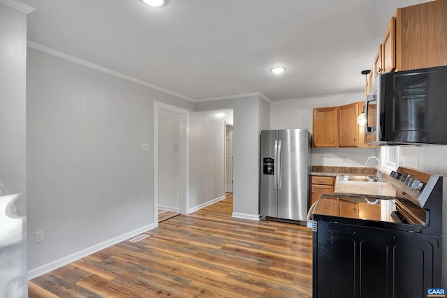 kitchen with stainless steel fridge, hardwood / wood-style flooring, stove, ornamental molding, and sink