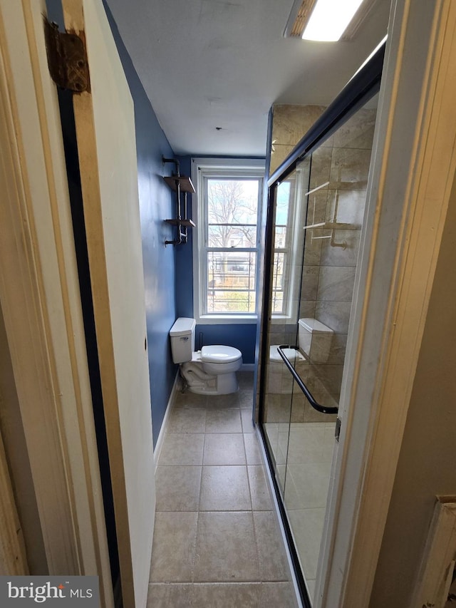 bathroom with tile patterned floors, a shower with shower door, and toilet