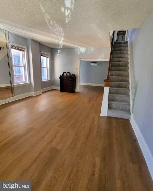 unfurnished living room with wood-type flooring and a textured ceiling