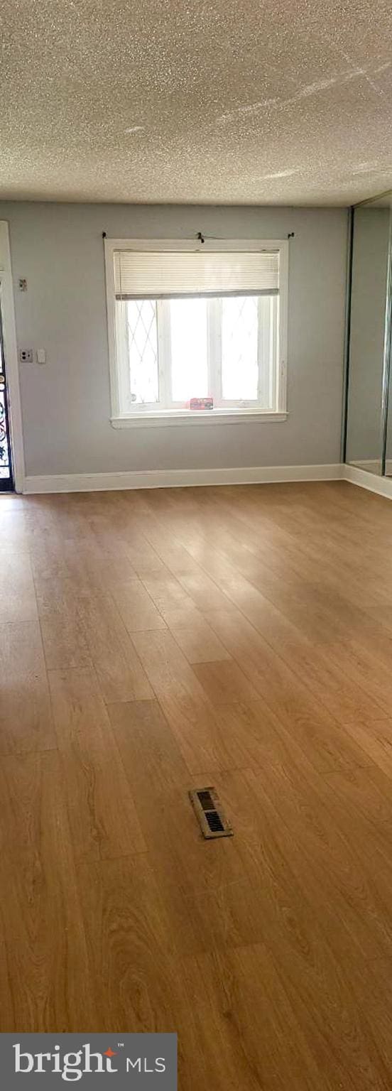 unfurnished room with wood-type flooring and a textured ceiling