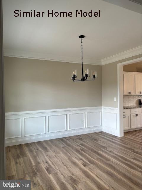 unfurnished dining area featuring light hardwood / wood-style floors, a notable chandelier, and crown molding