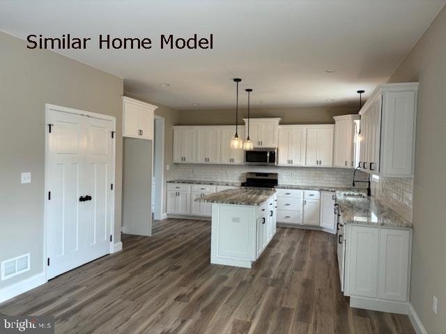 kitchen featuring a kitchen island, pendant lighting, white cabinetry, appliances with stainless steel finishes, and dark hardwood / wood-style flooring