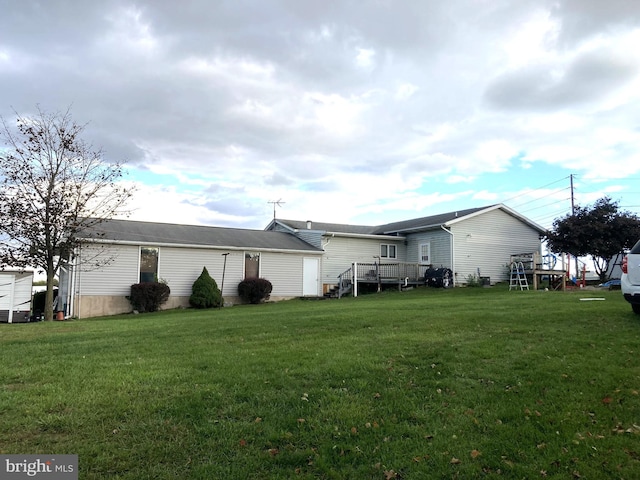 rear view of house with a wooden deck and a yard