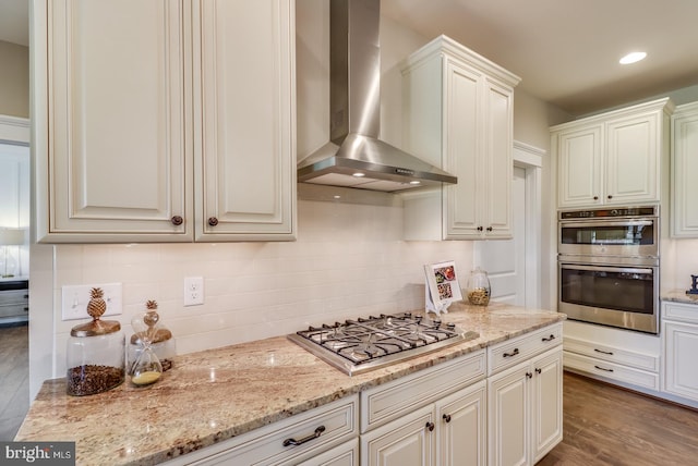 kitchen with white cabinets, wall chimney range hood, stainless steel appliances, and dark hardwood / wood-style flooring