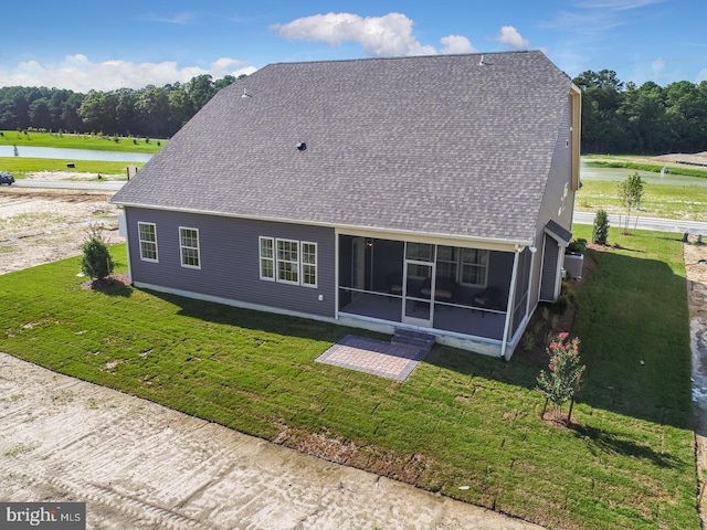 rear view of property featuring a yard, a water view, and a sunroom