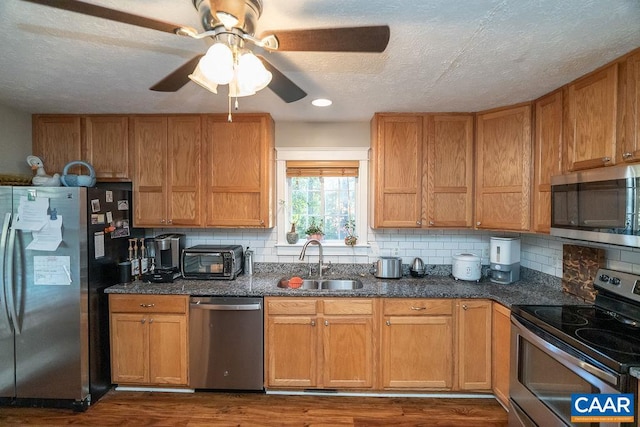 kitchen with decorative backsplash, stainless steel appliances, sink, a textured ceiling, and dark hardwood / wood-style flooring