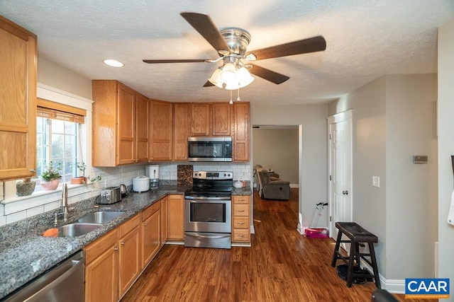 kitchen featuring ceiling fan, backsplash, dark wood-type flooring, sink, and stainless steel appliances