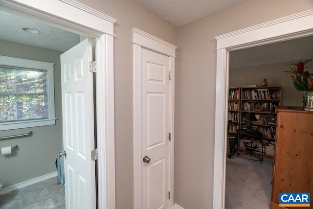 hallway featuring a textured ceiling and light colored carpet