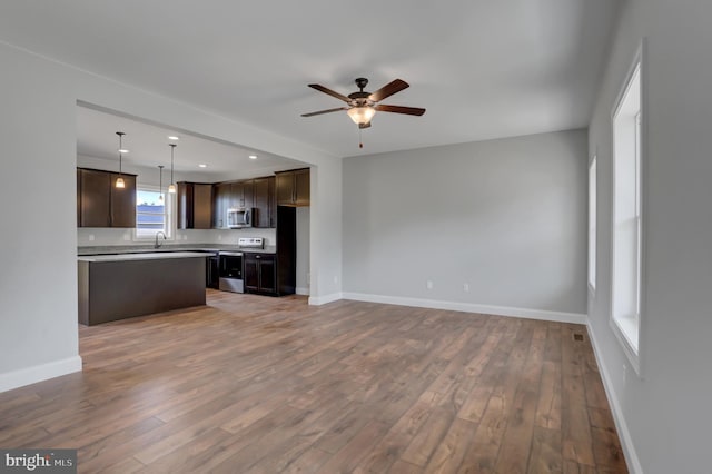 kitchen featuring stainless steel appliances, dark brown cabinetry, decorative light fixtures, and hardwood / wood-style floors