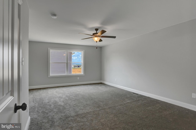 spare room with ceiling fan and dark carpet