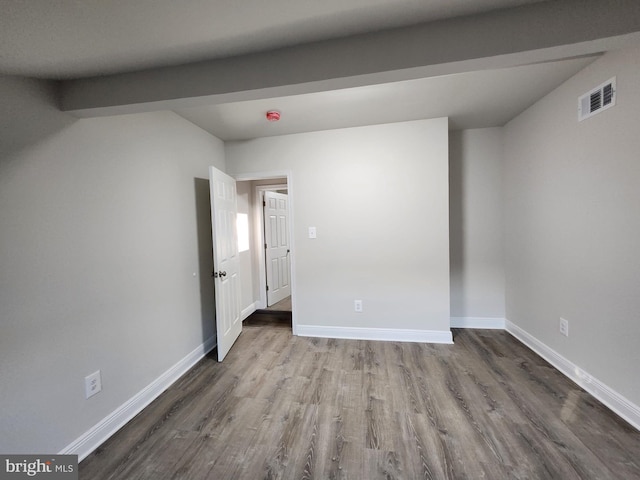 unfurnished room featuring hardwood / wood-style floors and beam ceiling