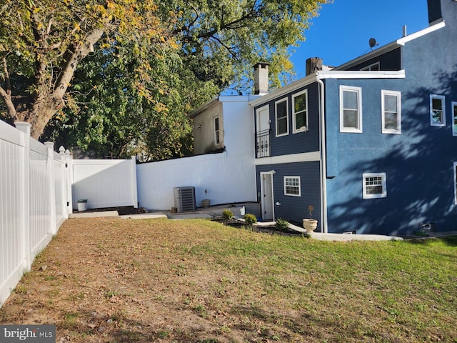 back of house with cooling unit and a lawn