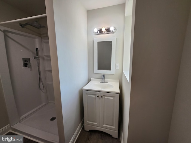 bathroom with hardwood / wood-style flooring, vanity, and a shower