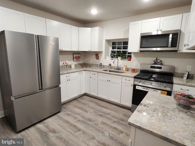 kitchen with white cabinets, sink, light wood-type flooring, and stainless steel appliances