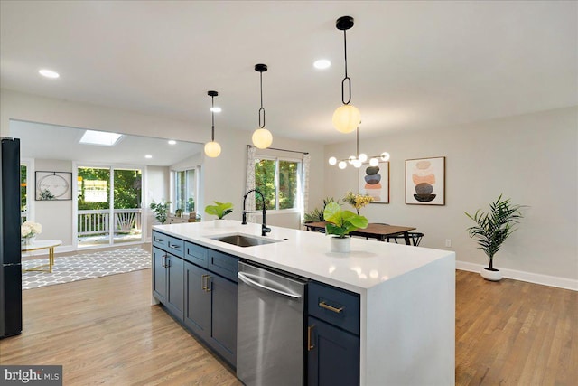 kitchen with stainless steel dishwasher, sink, hanging light fixtures, and a center island with sink