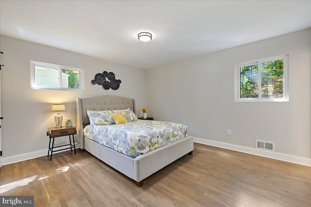 bedroom with wood-type flooring and multiple windows