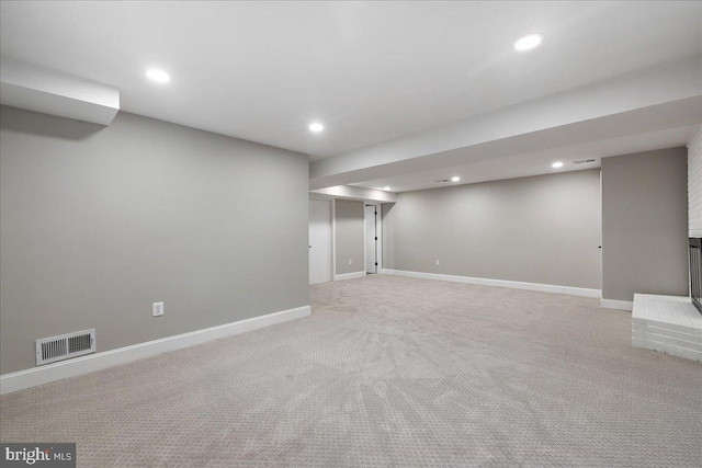 basement featuring light carpet and a fireplace