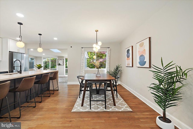 dining area featuring a chandelier, light wood-type flooring, and a skylight