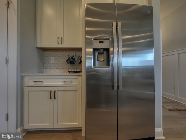 kitchen with decorative backsplash, white cabinets, stainless steel fridge with ice dispenser, and light hardwood / wood-style flooring