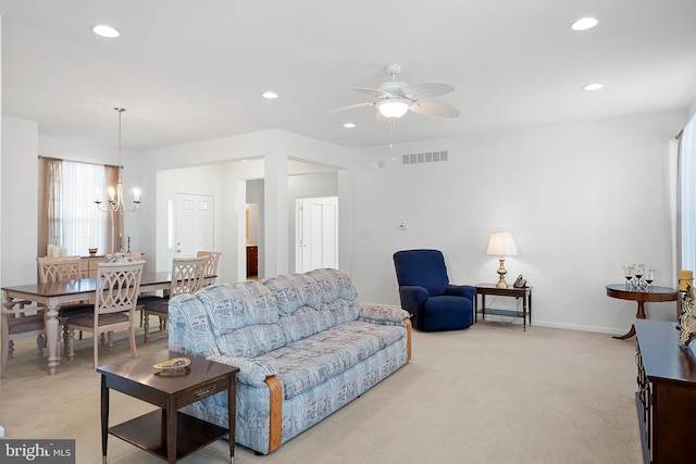 living room with ceiling fan with notable chandelier and light colored carpet