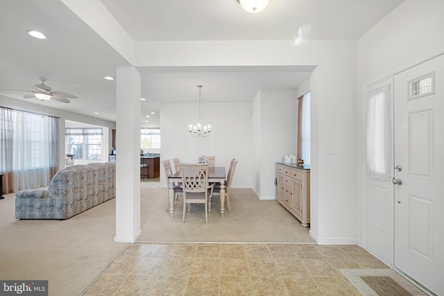 dining space featuring light carpet and ceiling fan with notable chandelier