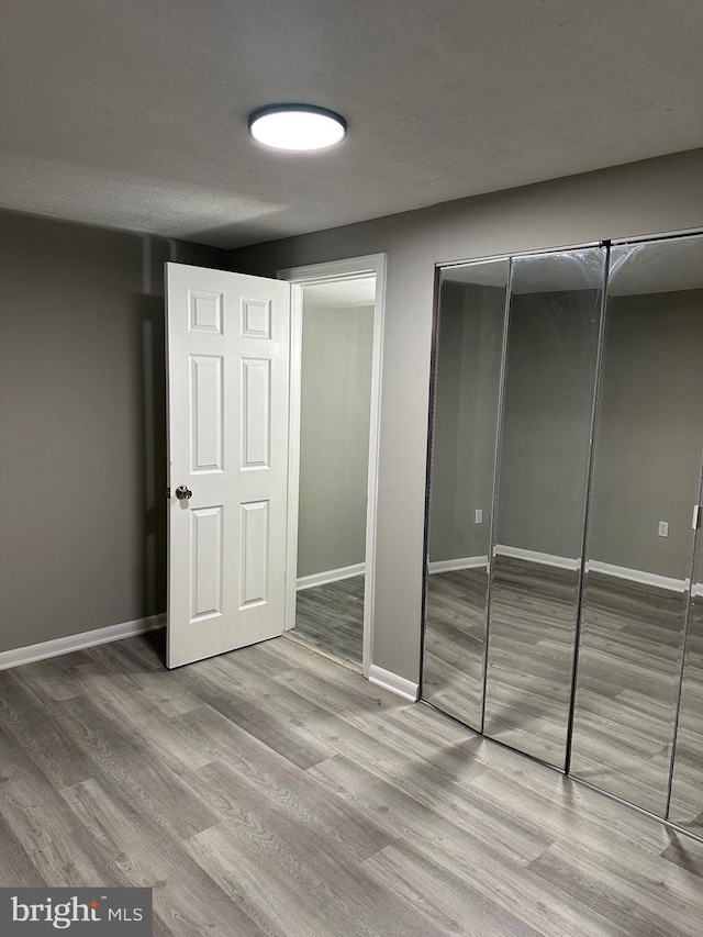 unfurnished bedroom with a textured ceiling and light wood-type flooring