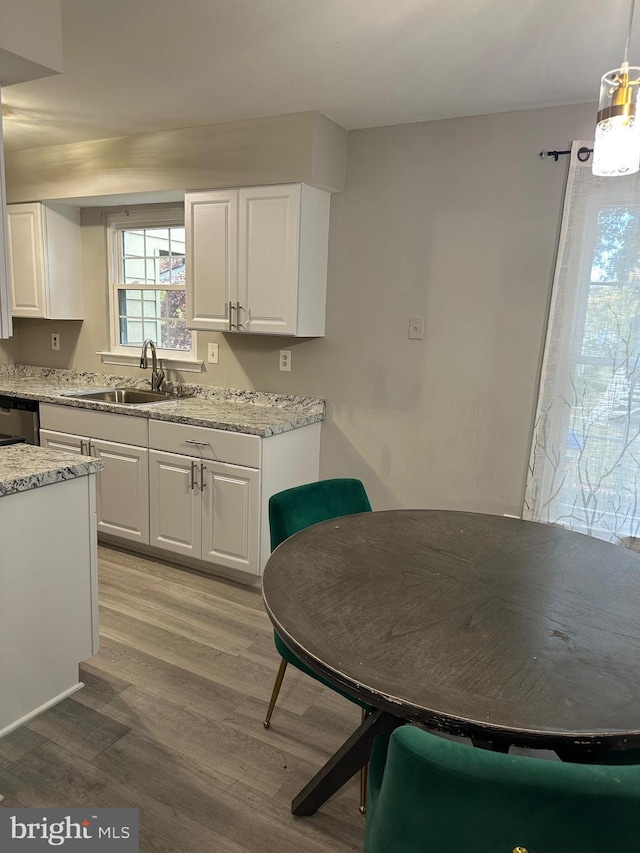 kitchen with sink, white cabinets, pendant lighting, and light wood-type flooring