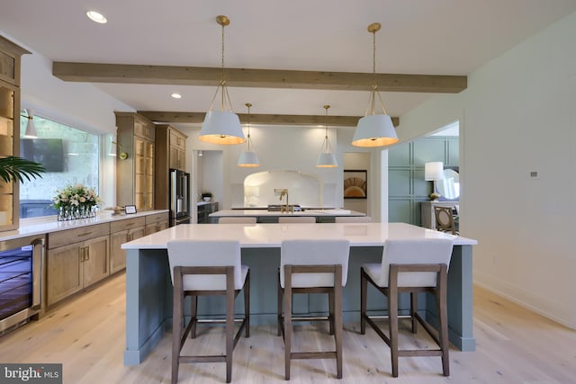 kitchen featuring a large island, light hardwood / wood-style floors, pendant lighting, and beverage cooler