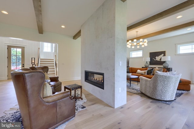 living room with light wood-type flooring, beamed ceiling, plenty of natural light, and a fireplace