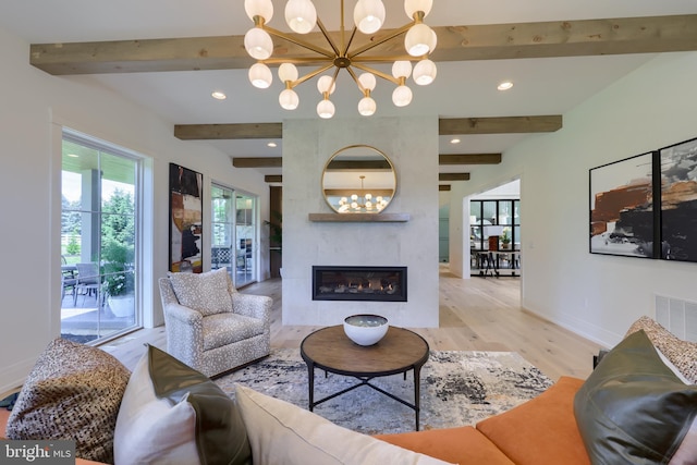 living room featuring a large fireplace, beamed ceiling, a chandelier, and light wood-type flooring