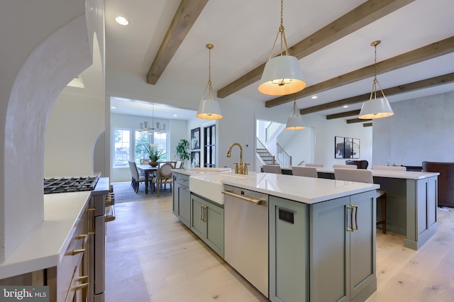 kitchen featuring sink, hanging light fixtures, stainless steel appliances, light hardwood / wood-style flooring, and a center island with sink